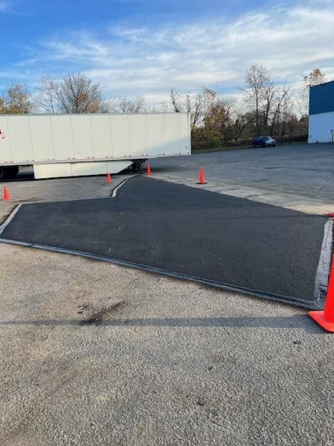 New asphalt patch repairing a damaged area of a commercial parking lot, taped off while it cures, by R. Stanley's Paving.