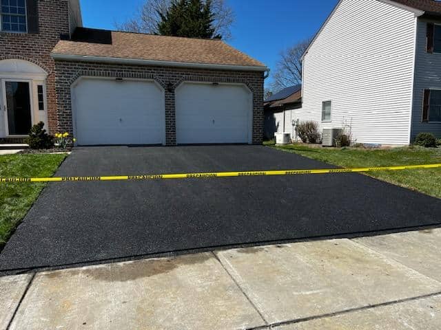 Freshly repaved asphalt driveway at a brick home in the Leesport area by R. Stanley's Paving.