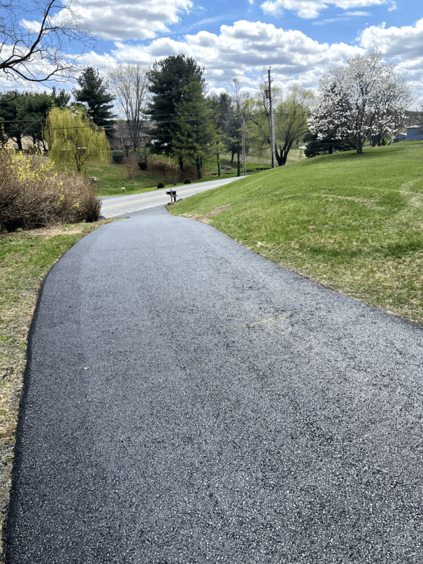 After: finished asphalt driveway curving across a hillside property.