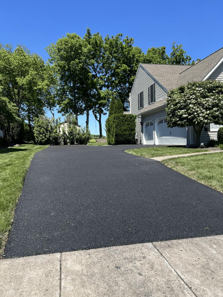 Freshly paved asphalt driveway beside a gray-sided two-story home in the Leesport area by R. Stanley's Paving.