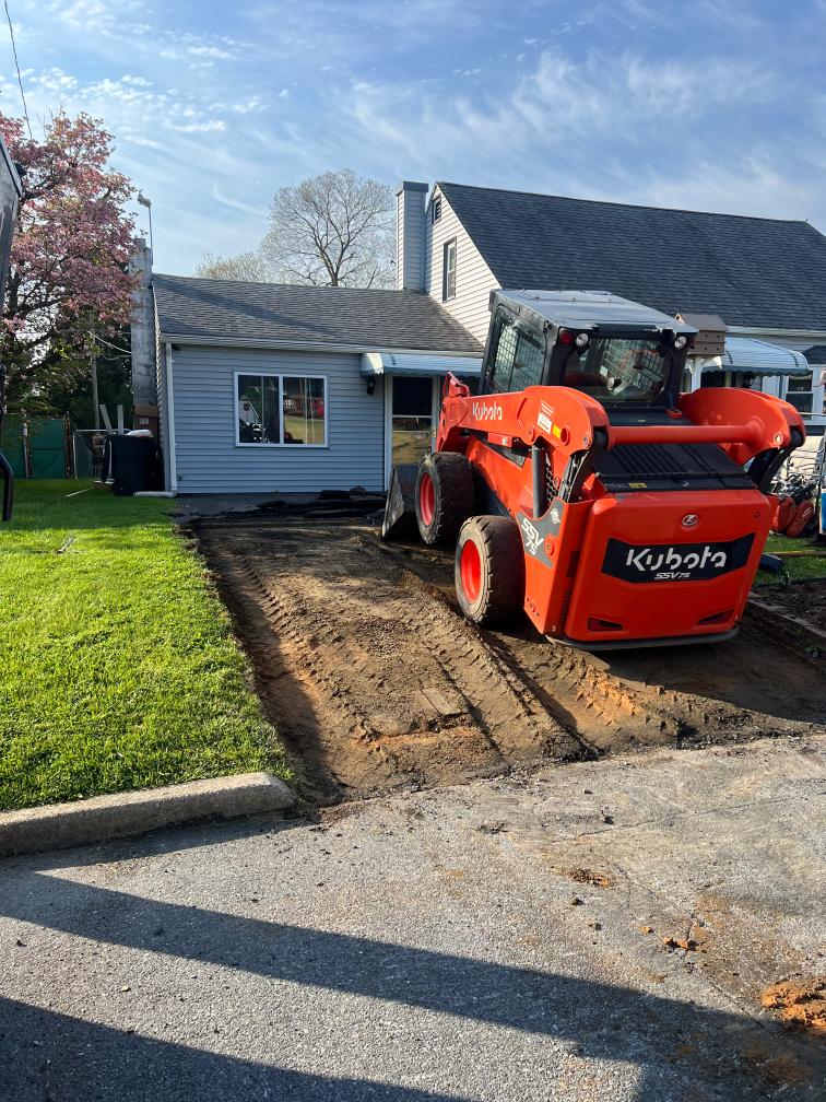 Before: skid steer removing an old driveway before new asphalt paving.